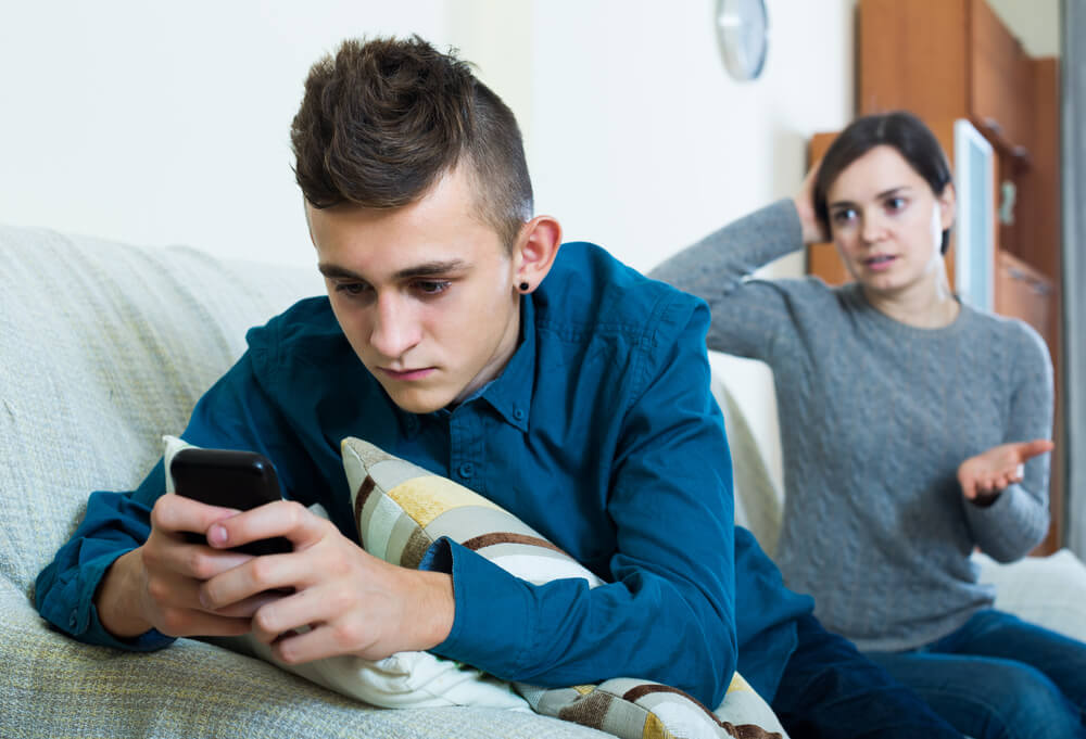 European,Teen,Age,Son,Playing,With,Phone,,Mother,Trying,To